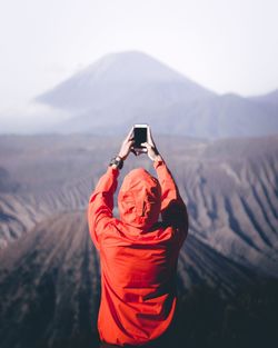 Rear view of man using mobile phone against sky