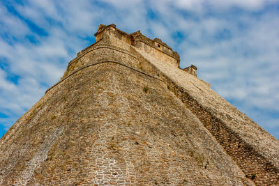 Low angle view of old ruin building against cloudy sky