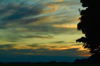 Low angle view of silhouette trees against dramatic sky
