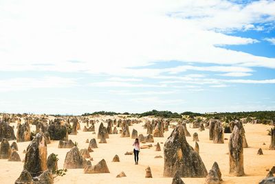 Woman standing by limestones at nambung national park against sky