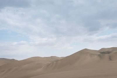 Scenic view of desert against cloudy sky