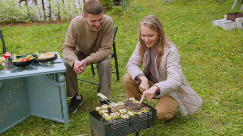Couple preparing food while sitting at yard