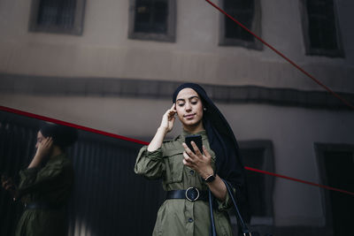 Portrait of modern muslim woman outdoors using her smartphone