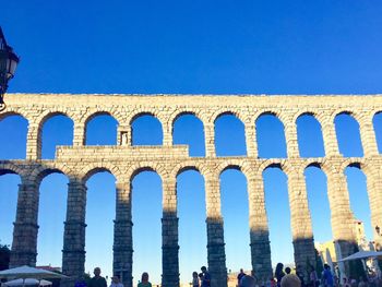 Low angle view of coliseum against clear blue sky