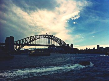 Bridge over river against cloudy sky