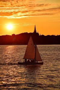 Silhouette sailboat sailing on sea against sky during sunset