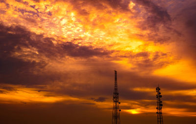 Low angle view of communications tower against orange sky