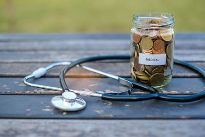 Jar with coins and stethoscope on table