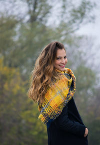 Portrait of smiling woman standing against trees