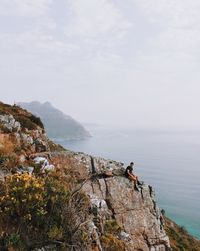 Scenic view of sea by mountain against sky