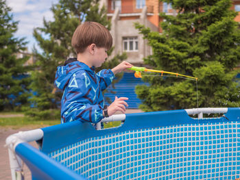 Boy is fishing in the paddling pool. leisure activity. playing kid.