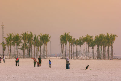 People at beach against clear sky