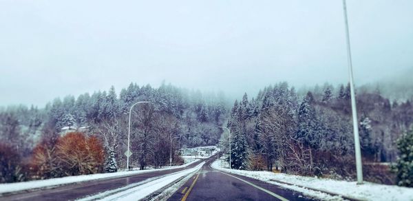 Road amidst trees against clear sky during winter