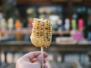 Close-up of hand holding corn on stick