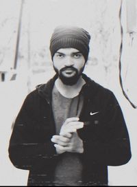 Portrait of young man standing against wall