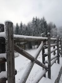 Close-up of snow on railing against sky during winter