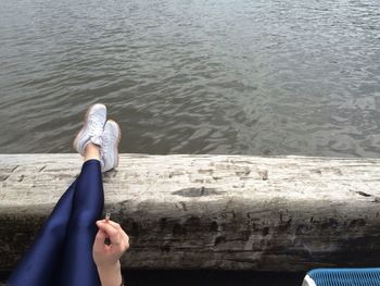 Low section of woman legs on retaining wall against lake