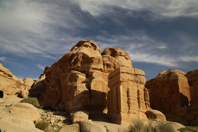 Low angle view of rock formations against cloudy sky