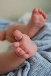 Low section of baby feet on bed at home