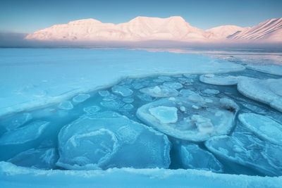 Scenic view of sea and snowcapped mountains against sky