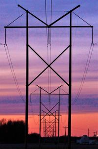 Silhouette electricity pylon against sky at sunset