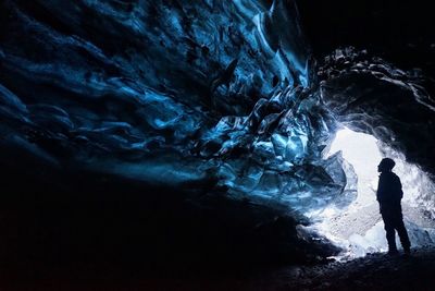 Silhouette man standing on rock in cave