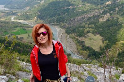 Portrait of smiling young woman against landscape