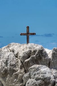 Close-up of cross on rock against sea