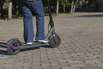 Low section of man riding push scooter on street