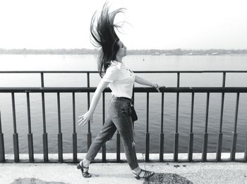 Side view of woman walking by railing on bridge with tousled hair