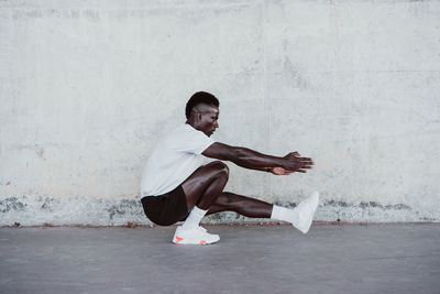 Male athlete doing exercise by white wall