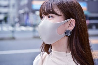 Close-up of woman wearing flu mask standing outdoors