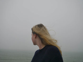 Side view of woman against sky during foggy weather