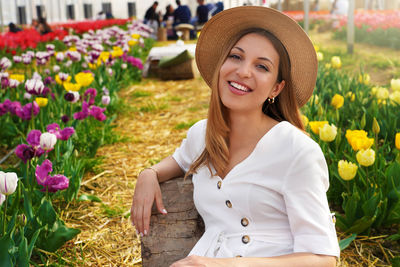 Portrait of smiling girl sitting relaxed between tulips fields on springtime. looking at camera.