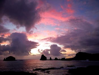 Scenic view of sea against dramatic sky during sunset