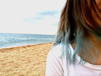 Midsection of woman at beach against sky