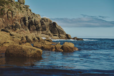 Rock formation in sea against sky