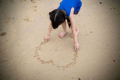 High angle view of girl making heart shape at beach