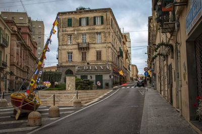 Empty road amidst buildings in city