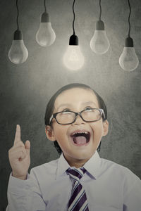 Thoughtful boy looking at light bulbs while standing against wall