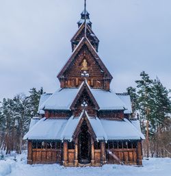Old church structure by trees against sky during winter
