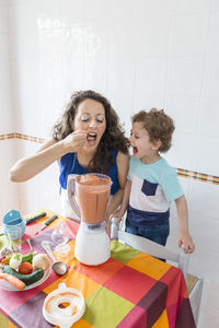 Woman tasting food while standing by son