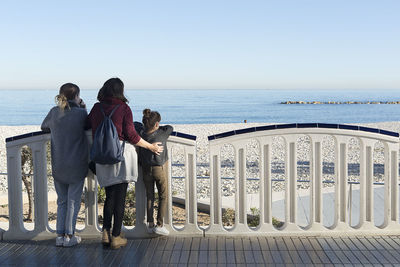 Friends standing on beach against clear sky