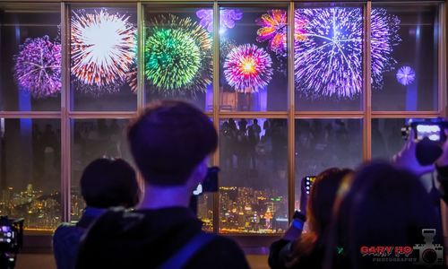 Rear view of people watching firework display at night