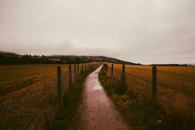 Road amidst field against sky