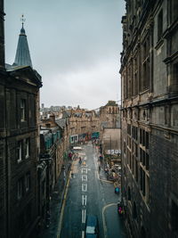 Vehicles on road amidst buildings in city against sky