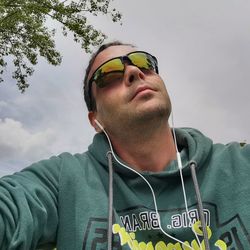 Portrait of young man wearing sunglasses standing against sky