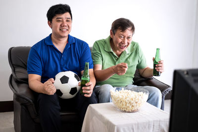 Family with food and drink watching sports on tv at home