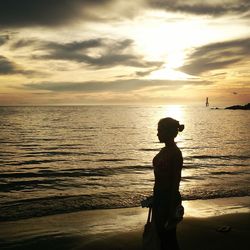 Silhouette woman standing at beach during sunset