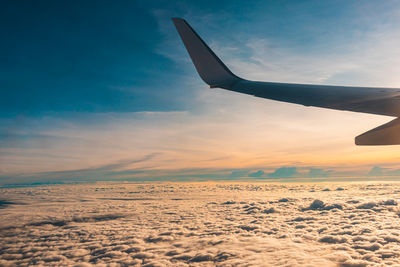 Airplane flying above the clouds at sunset.